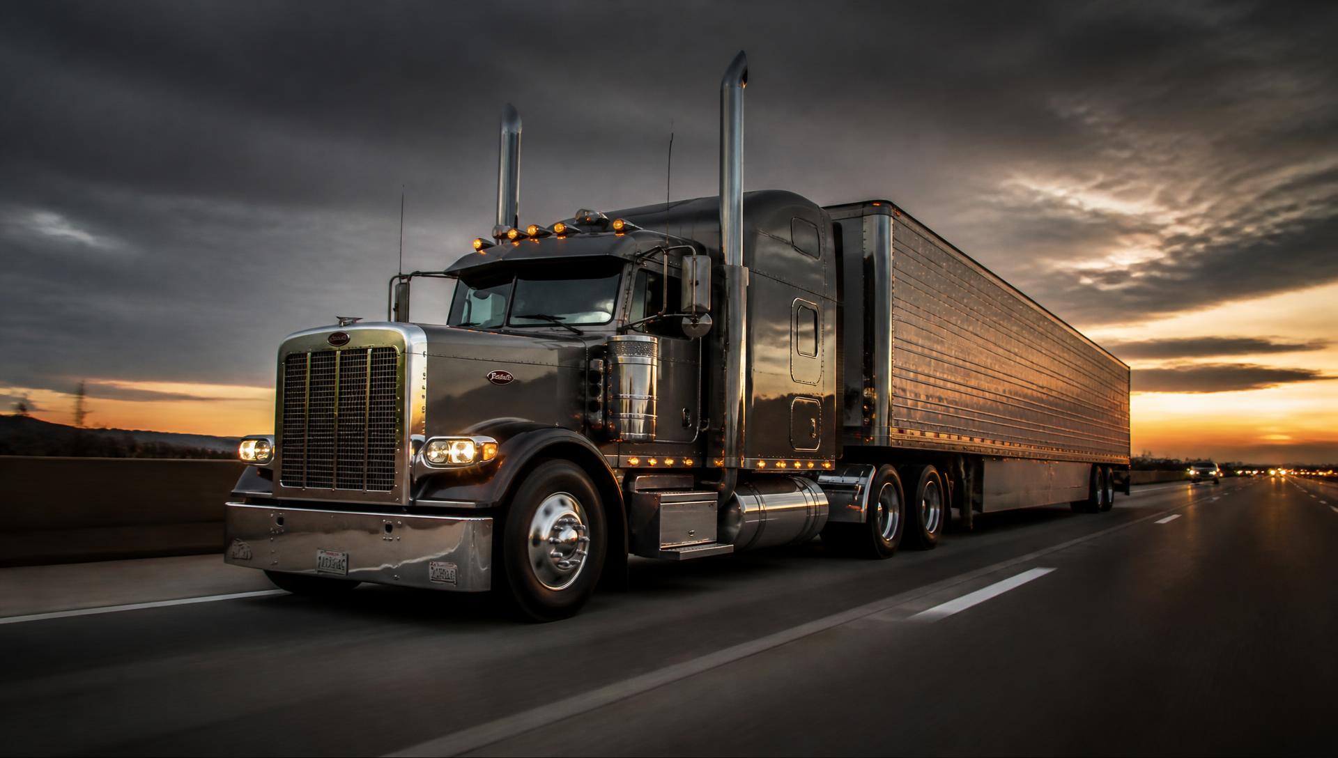 Modern American Class 8 semi truck on a US interstate highway at dusk
